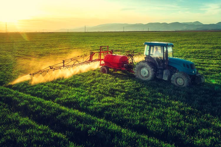 tractor spraying field - farm is protected by CrossRoads farm insurance in Iowa