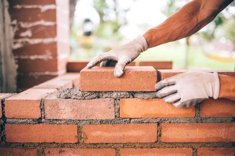 Construction worker building brick structure - contractor company protected by CrossRoads insurance services